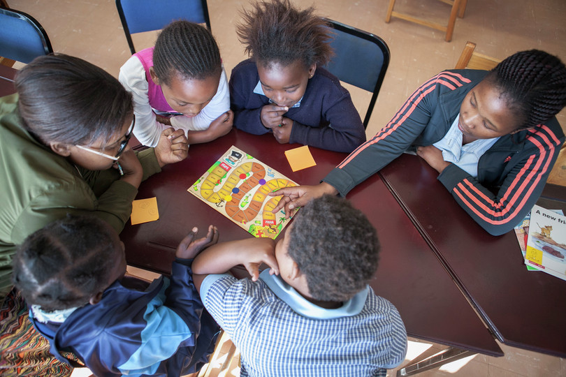 A group of children play a reading game together
